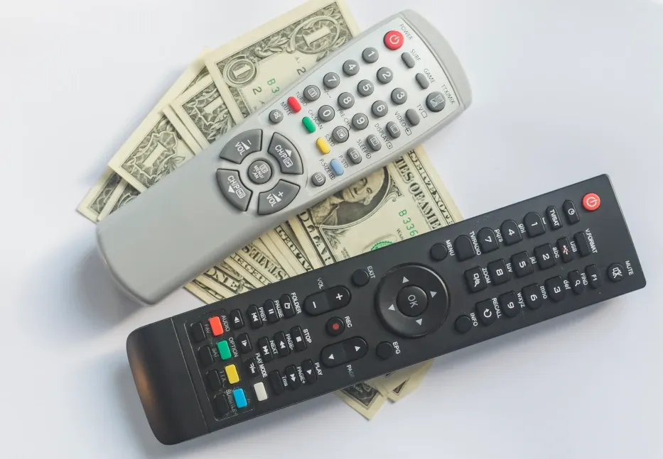 Cable TV cord being cut with cash money.
